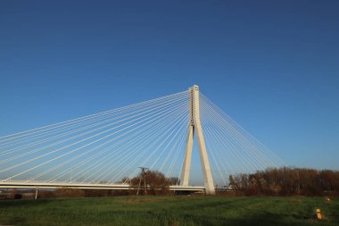 Rzeszow, Polonya - 99 2018: Wislok Nehri üzerindeki askıya alınmış yol köprüsü. Metal inşaat teknolojik yapısı. Modern mimari. Mavi arka planda beyaz bir haç şehrin bir sembolüdür..