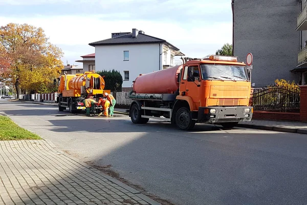 Küçük bir Avrupa kasaba sokaklarında özel teknik araçlarla takas kanalizasyon. Turuncu arabalar ve belediye çalışanları enkaz ve kir şehirden temiz. Altyapı.