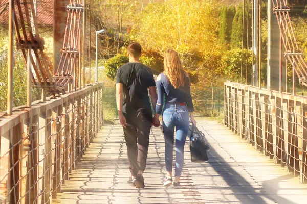 年轻夫妇 男孩和女孩走在桥上的秋天牵手 浪漫男人和女人之间的关系 人们之间的爱的表现 在清新的空气中行走 常见方式 — 图库照片