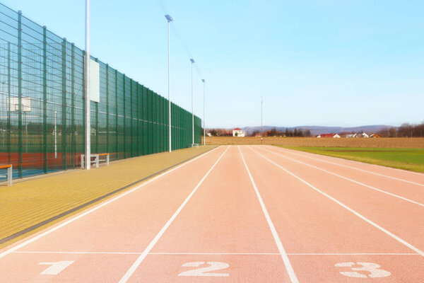 Красная беговая дорожка на стадионе. Элемент спортивного комплекса. Наружное покрытие для спорта. Место для соревнований по легкой атлетике. 1, 2, 3 - стартовые номера треков
