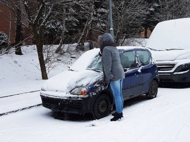 Kış karla kaplı otomobillerde. Soğuk hava. Kirli trafik. Kadın araba park üzerinde kar yağıyor.