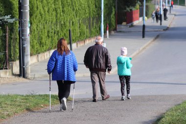 İskandinav/kuzey yürüyüşü. Bir kadında şehir yürüyüş summer'ın otların arasında güneş ışınları yoluyla. Sağlıklı bir yaşam tarzı. Spor olay. Toplum bir örnek. Yaşlı kişiler için etkinliği