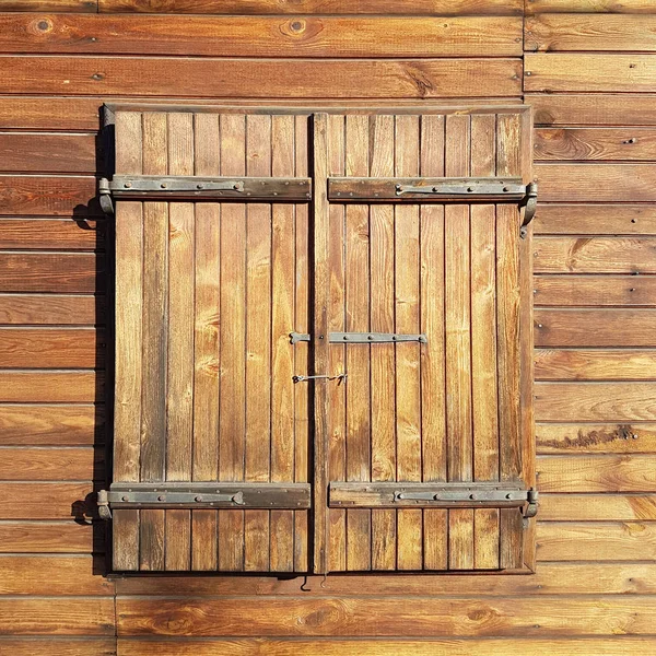 在木墙上用木百叶窗关上的窗户 锻造金属窗帘 古老的建筑和传统的设计 在建造房屋时使用木材 用钉子固定的木板 — 图库照片