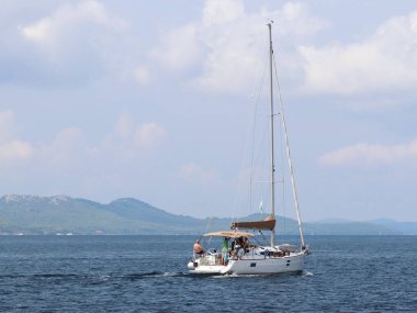 Bir Yelkenli tekne bir koyda demirlemiş olan. İnsanlar denizde yıkarım. Akdeniz Bölgesi Adriyatik Denizi üzerinde aktif dinlenme. Dalmaçya riviera Hırvatistan. Prestijli ve zengin yaşam tarzı