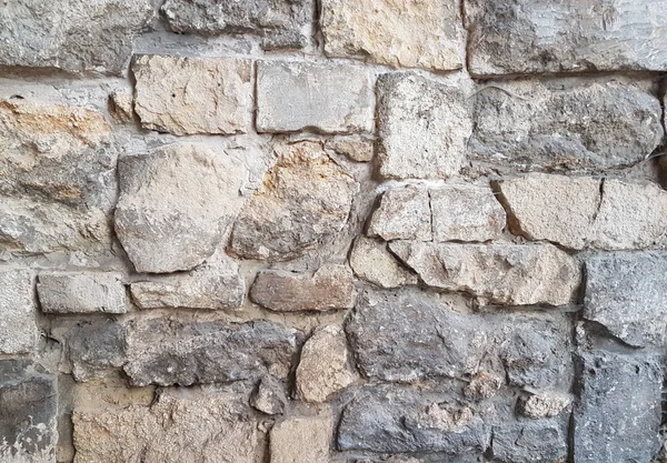 Ancient medieval stone masonry. Texture of a fragment of a wall of an old structure. A background for design and creative work. Decoration and exterior decoration of the building. Construction works.