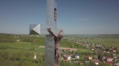 Kolaczyce, Polonya - 10 Mayıs 2018: Yerleşimlerin ortasındaki bir tepede çarmıha gerilmiş İsa'nın büyük bir heykeli. Hıristiyan inananların dini işareti. Metalden heykel. Kuş bakışı. 