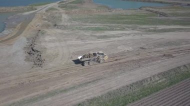 Vislock Nehri, Polonya - 2 Mayıs 2018: Ekskavatör damperli kamyon toprak ile yükler. Kara nehir çakıl ocağında çalışıyor. Droning sinek Cat.Panorama tarafından üretilen özel bir teknik çalışma