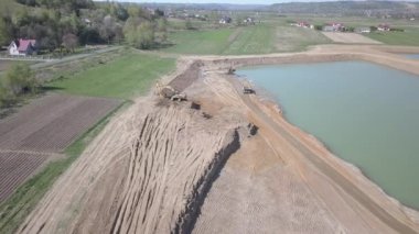 Vislock Nehri, Polonya - 2 Mayıs 2018: Ekskavatör damperli kamyon toprak ile yükler. Kara nehir çakıl ocağında çalışıyor. Droning sinek Cat.Panorama tarafından üretilen özel bir teknik çalışma