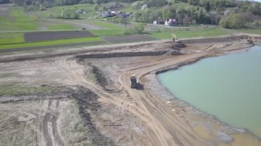 Vislock Nehri, Polonya - 2 Mayıs 2018: Ekskavatör damperli kamyon toprak ile yükler. Kara nehir çakıl ocağında çalışıyor. Droning sinek Cat.Panorama tarafından üretilen özel bir teknik çalışma