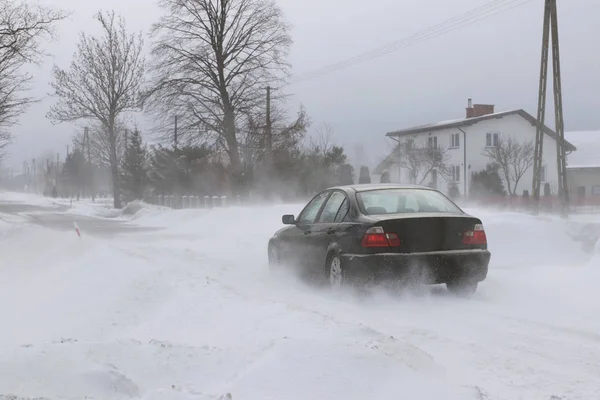 一辆汽车在一条被雪覆盖的危险道路上偷偷穿过漂流 私人交通工具正在与冬季因素作斗争 雪灾期间交通困难 寒冷天气的后果 — 图库照片