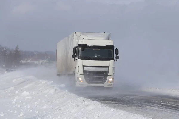 一辆大卡车在一条被雪覆盖的危险道路上偷偷穿过雪堆 Tir 与冬季元素作斗争 雪灾期间交通困难 寒冷天气和水的后果 — 图库照片