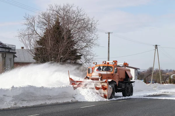 一辆有犁的大车把道路从雪中清理干净 橙色货物专用设备在冬季与元素作斗争 消除雪灾的影响 交通困难 冷冻水 — 图库照片