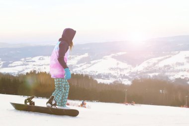 Kız snowboard slalom için hazırlanıyor karla kaplı dağlar, arka plan üzerinde durmak. Kış sporları için modern spor malzemeleri. Dağ tatil. Açık havada fiziksel aktivite.