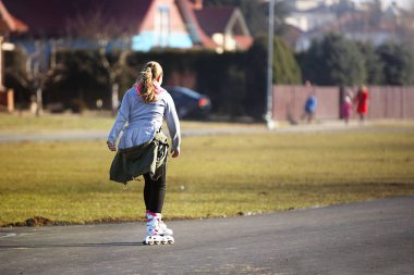Bahar sezonu yeni bir asfalt yolda silindirler üzerinde Kız biniyor. Gençlik etkinliği ve sağlıklı bir yaşam tarzı. Spor eğitim ve rekabeti severler. Spor malzemeleri kullanımı. Zafer peşinde