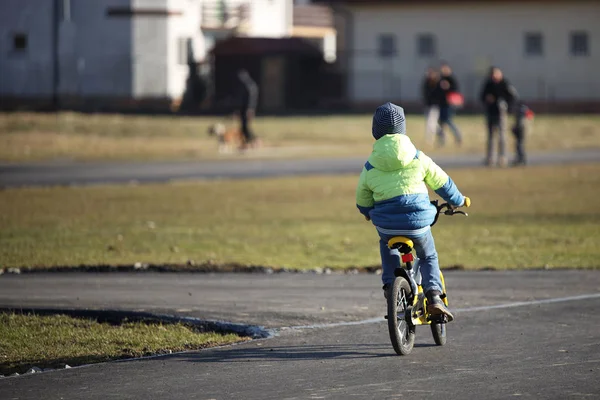 Ein Junge in Halbjahreskleidung fährt mit dem Fahrrad auf einer asphaltierten Straße. Die jüngere Generation treibt Sport und verbringt ihre Freizeit aktiv an der frischen Luft. Spiele auf der Straße. Freude der Kinder — Stockfoto