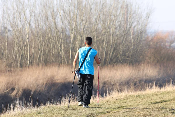 Caminhada nórdica escandinava. Um homem de roupas esportivas passeia pela grama da primavera nos raios da luz solar. Estilo de vida saudável. Evento desportivo. Um exemplo de sociedade — Fotografia de Stock