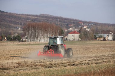 Bir çiftçi bir sembol ile kırmızı bir traktör tahıl köyü alan özel bir alanda sürülmüş topraklarda sows. Mekanizasyon bahar saha çalışması. Çiftçinin günlük yaşam. Toprak işleme. Tarım