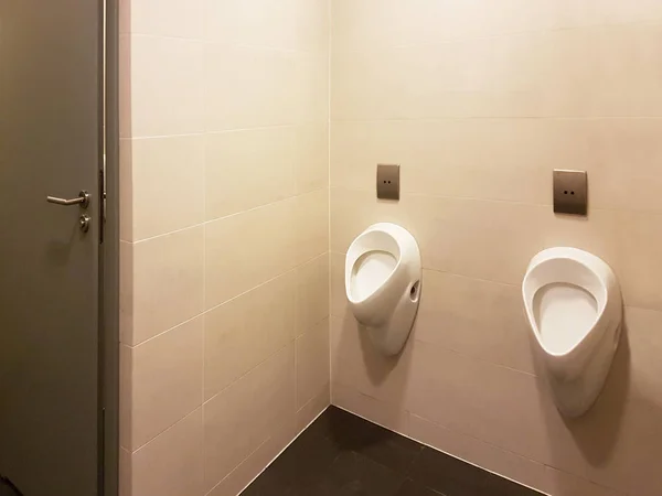 Interior do banheiro em cores bege e branco claro. Urinal de cerâmica oval. Urinal de cerâmica oval. Local de necessidade de homens. Banheiro em áreas públicas de infra-estrutura urbana. Interior dos espaços públicos — Fotografia de Stock