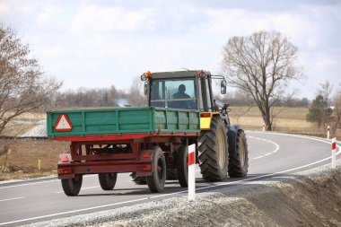 Asfalt yolda römork sürmek bir traktör. Tarım taşımacılığında arka görüş. Bölgesel bir yolda çiftlik ürünlerinin taşınması. Tarımsal Sanayi kompleksinin mekanizasyonu. Hasat