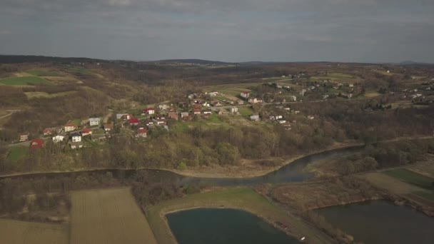 鳥瞰図から見たパノラマ 中央ヨーロッパ ポーランドの村は緑の丘と川の間に位置しています 温暖気候 フライトドローンまたはクワッドコプター 景観の都市化 — ストック動画