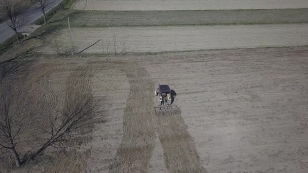 一个农民在拖拉机上 带着播种机在村地区的一块私人田地里犁地里播种粮食 春季田间作业的机械化 农民的日常生活 土地加工 — 图库视频影像