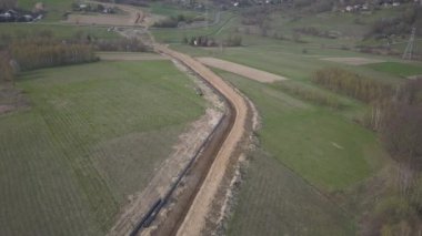 Yeşil tepelerin arasına gaz boru hattı döşenmesi. Kazılan sipere dalmak için hazırlanmış büyük yüksek basınçlı çelik borular. Stratejik endüstride arazi işleri. Enerji ve doğal kaynaklar