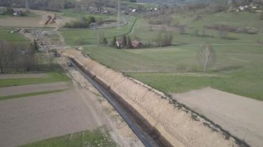 Yeşil tepelerin arasına gaz boru hattı döşenmesi. Kazılan sipere dalmak için hazırlanmış büyük yüksek basınçlı çelik borular. Stratejik endüstride arazi işleri. Enerji ve doğal kaynaklar