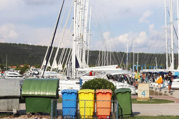 Різнокольорові пластикові сміттєві балончики для сортування сміття знаходяться на набережній в Марині на тлі вітрильних яхт. Прибирання яхти після Статуту. Переробка та утилізація сміття — стокове фото