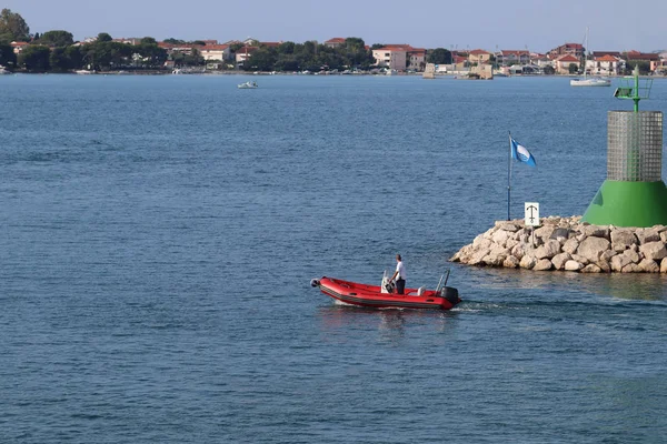 Людина в надувному моторному човні, плаває повз кам'яній воді з небезпечним сигналом маяка. Відпочинок на воді в раю. Середземноморський круїз на чартерному судні. Пілот та персонал Марина — стокове фото