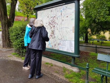 Krakow, Polonya - 5 9 2019: İki yaşlı kadın turist şehrin haritasını görüyor. Şehir merkezinde bir rota arayın. Turistik yerlerin yeri. Sakin ve ilginç bir yaşlılık. Tarihi yerlere seyahat