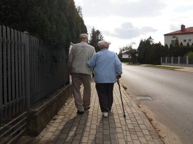 Kaldırım boyunca el ele tutuşarak yol boyunca yaşlı insanlar yürüyüş çifti. Büyükbaba ve Büyükanne bir yerleşim bölgesinde bir yolda. Yaşlı hareketi sağlık. Mutlu yaşlılık