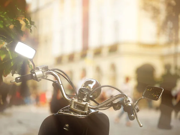 View through the steering wheel of a motorcycle from the biker side on the architecture of the ancient city. Chopper parking in the tourist center. Traveling on two-wheeled vehicles. Against the back