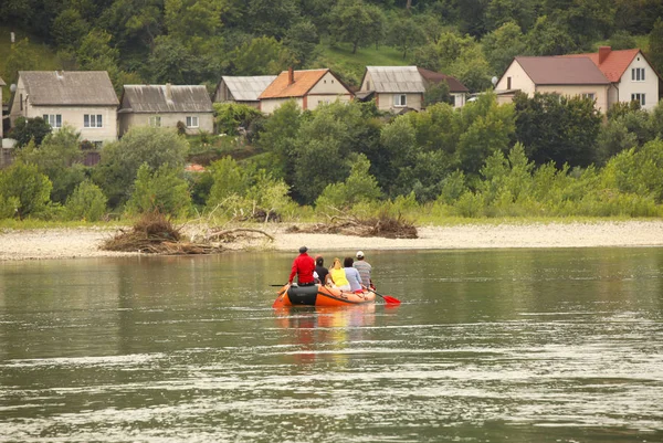 Skupina turistů se Raje na horské řece na pontopon. Turistické trasy Transcarpathie na Ukrajině. Rafting na řece Tissa. Bezpečnost na vodě. Záchranný člun a muž za botem-mafián. — Stock fotografie