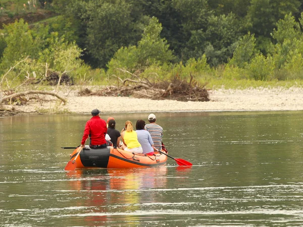 Skupina turistů se Raje na horské řece na pontopon. Turistické trasy Transcarpathie na Ukrajině. Rafting na řece Tissa. Bezpečnost na vodě. Záchranný člun a muž za botem-mafián. — Stock fotografie