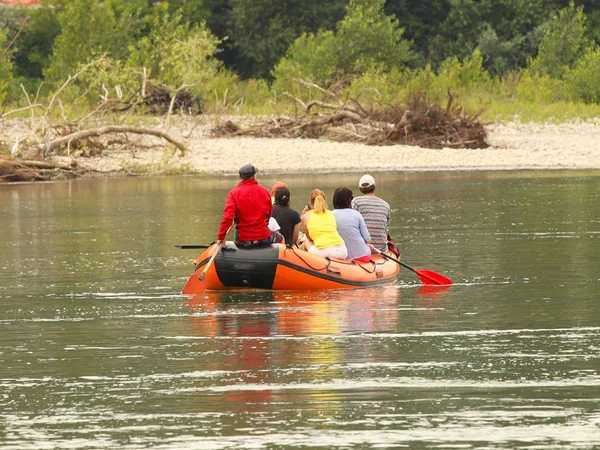 Skupina turistů se Raje na horské řece na pontopon. Turistické trasy Transcarpathie na Ukrajině. Rafting na řece Tissa. Bezpečnost na vodě. Záchranný člun a muž za botem-mafián. — Stock fotografie