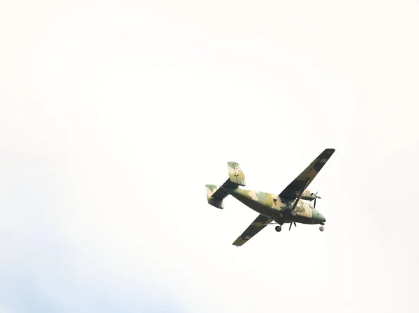 A light military landing turboprop aircraft of the Polish Armed Forces flies across the sky with landing gears released. Landing at NATO Air Force Base. Meteorology and weather forecast for aviation — Stock Photo, Image