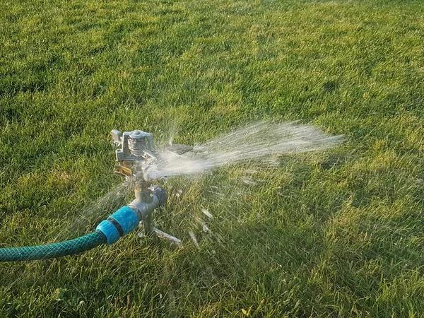 水雾浇灌青草草坪 绿地灌溉系统 照顾英国的草坪 在自家花园节约用水 用水浇灌花园的套索和装置 — 图库照片