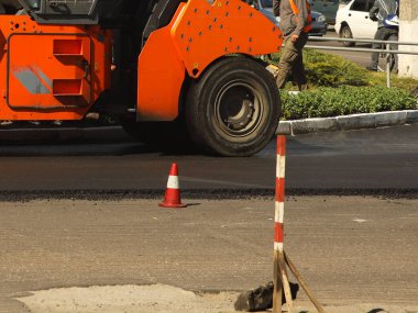 Ağır özel ekipmanların yardımıyla asfalt döşemek. Yolun inşaatı. Katı bir yüzeye sahip otoyol döşeyen modern teknolojiler. İnsanlar şantiyede çalışıyor. Yuvarlanan asfalt
