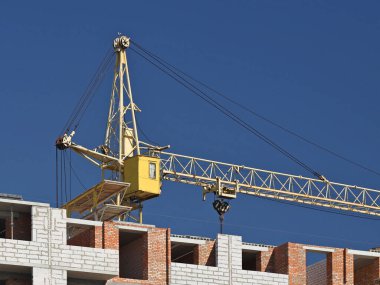 Tulumlu iki vinç operatörü, çok katlı bir binanın inşaatı sırasında çalışan yüksek katlı bir vinç tamir ediyorlar. Yüksekken riskli iş. Ağır inşaat malzemeleri kaldırılıyor. Şehir Geliştirme.