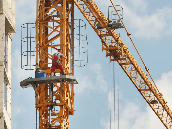 在一幢多层建筑的施工过程中 工装裤的起重机工人正在修理正在施工的一座高层塔式起重机 高风险的工作在高处 吊起重型建筑材料 城市发展 — 图库照片