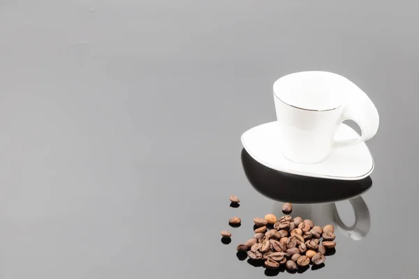 Taza de café blanco con granos de café sobre el fondo gris espejo — Foto de Stock
