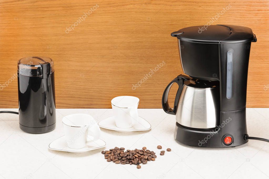Coffee machine with pot and handful coffee beans on the wood and