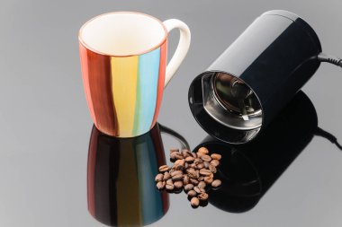 Gri ayna arka üzerinde kahve fasulyesi ve kupa ile çay değirmeni