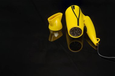 Siyah ayna arka planda sarı katlanabilir saç kurutma makinesi ile c