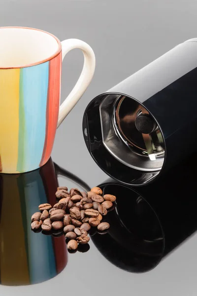 Moedor de café com grãos de café e caneca no backg espelho cinza — Fotografia de Stock