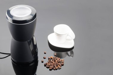 Gri ayna backg üzerinde coffe fasulye ve fincan ile Kahve öğütücü