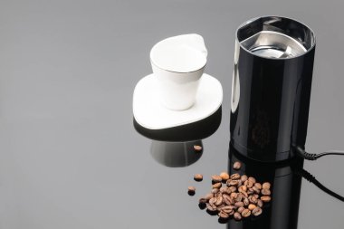 Gri ayna backg üzerinde coffe fasulye ve fincan ile Kahve öğütücü