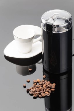 Gri ayna backg üzerinde coffe fasulye ve fincan ile Kahve öğütücü