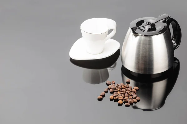 Caffettiera con chicchi di caffè e tazza sul backgroun specchio grigio — Foto Stock