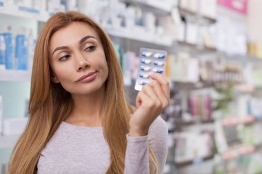 Genç güzel kadın şaşkın, seyir alanı kopyalayın blister Pills eczaneden, holding. Kadın müşteri karıştı, eczane, doğru ilaç seçimi. İlaç, çare kavramı